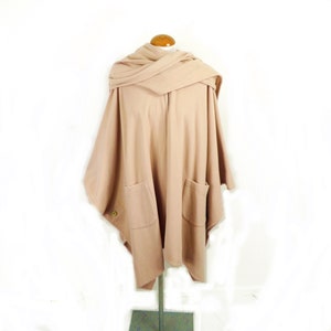 May include: A light brown poncho with a matching scarf, featuring two large pockets and a button closure.