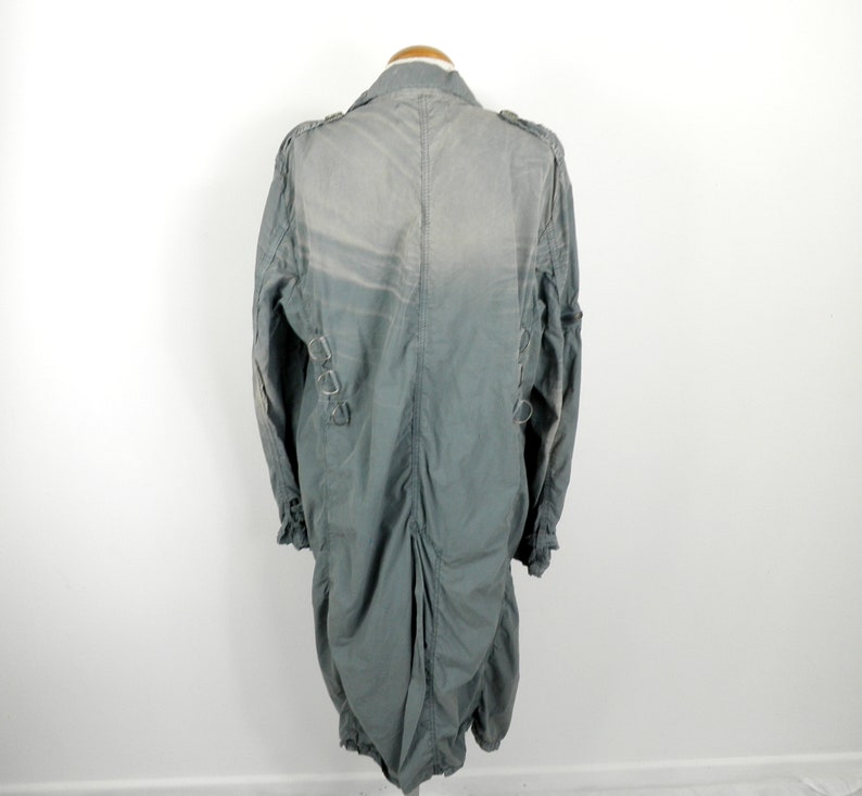 May include: A long, gray, lightweight jacket with a zipper closure and a stand-up collar. The jacket has a cinched waist and a slightly gathered back.