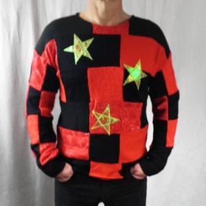 Peut inclure: Un pull à carreaux rouges et noirs avec des étoiles vertes en forme de décoration.