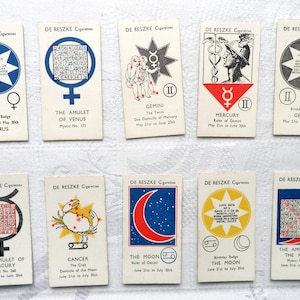 Puede incluir: Una colección de tarjetas de cigarrillos De Reszke vintage con símbolos astrológicos y texto. Cada tarjeta muestra signos del zodiaco como Tauro, Géminis y Cáncer, junto con información relacionada. Las tarjetas tienen un fondo crema con varios colores e ilustraciones.