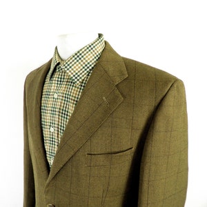Op de afbeelding: Een bruin tweed blazer met een subtiel geruit patroon. De blazer heeft een enkele knoopsluiting en een klepzak aan de linkerkant.
