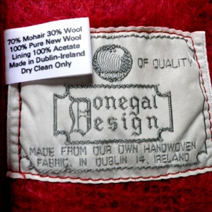 May include: White label with black text that reads "70% Mohair 30% Wool 100% Pure New Wool Lining 100% Acetate Made in Dublin-Ireland Dry Clean Only" and a larger label with black text that reads "OF QUALITY Donegal Design MADE FROM OUR OWN HANDWOVEN FABRIC IN DUBLIN 14, IRELAND".