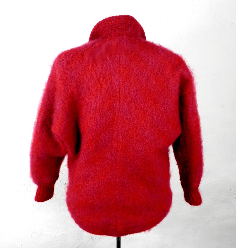 May include: A red fuzzy sweater with a high neck and long sleeves.