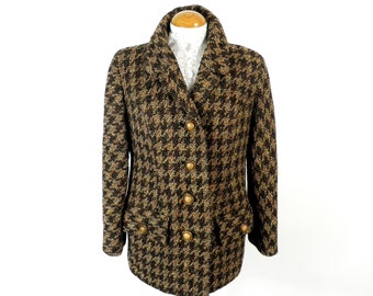 Könnte beinhalten: Eine braune und schwarze Tweedjacke mit goldenen Knöpfen. Die Jacke hat einen Kragen und einen doppelreihigen Verschluss.