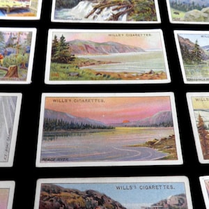 May include: A collection of vintage cigarette cards featuring scenic landscapes. The cards are printed with the text "Wills's Cigarettes" and depict scenes such as a frozen lake, a river, and a mountain range.