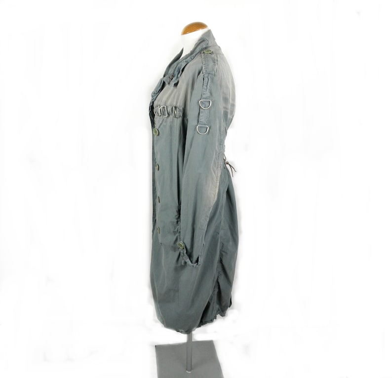 May include: A long, gray,  cotton jacket with a  ruched detail on the front and a  lace-up back. The jacket has a  button closure and  two large metal rings on the sleeves.