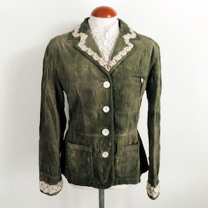 May include: A green corduroy jacket with a white lace trim around the collar and cuffs. The jacket has a button-up front and two pockets.