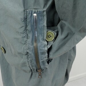 May include: A green utility jacket with a zippered pocket on the sleeve and a button closure. The jacket has a relaxed fit and a casual style.