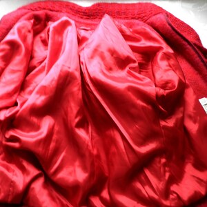 May include: Red wool jacket with a red satin lining. The jacket has a zipper closure and a label on the inside.