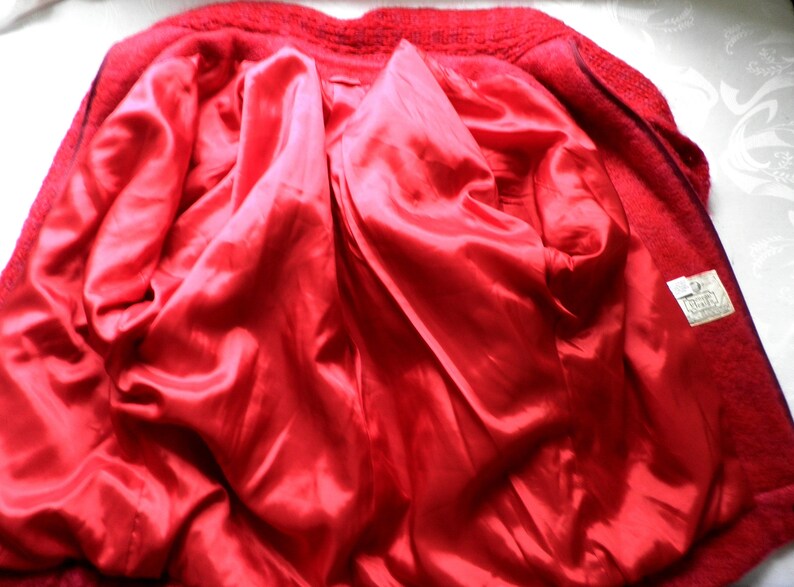 May include: Red wool jacket with a red satin lining. The jacket has a zipper closure and a label on the inside.