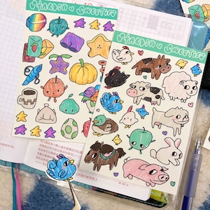 May include: Two sheets of stickers featuring hand-drawn illustrations. The first sheet features a variety of colorful stickers, including a pumpkin, a star, a cup of coffee, and a bird. The second sheet features a variety of farm animal stickers, including a cow, a pig, a sheep, and a horse. The text "SHARDEW SWEETIGS" is printed on both sheets.