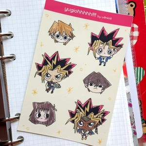 May include: A sheet of stickers featuring cartoon illustrations of characters from the anime series Yu-Gi-Oh!. The stickers include characters with spiky hair and various outfits. The text "yugiohhhh!!!" is printed at the top.