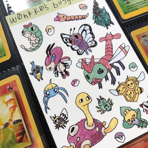May include: A sheet of paper with colorful hand-drawn illustrations of various bug-like creatures, including a butterfly, a bee, and a turtle-like figure. The text "Wonkko's buggies" is written at the top. The sheet is surrounded by Pokémon cards.