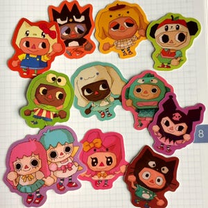 May include: A collection of colorful die-cut stickers featuring cartoon characters in various animal costumes. The stickers showcase a variety of outfits and expressions, with a focus on bright colors and playful designs. The stickers are arranged on a white background.