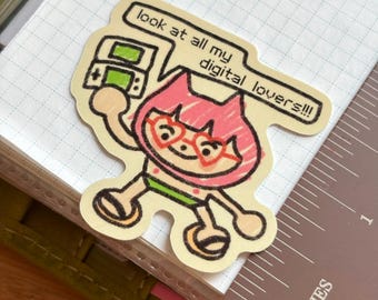 May include: A die-cut sticker showing a cartoon character with pink hair, heart-shaped glasses, and a green outfit, holding a handheld gaming device. The speech bubble says, "look at all my digital lovers!!!" The sticker is on a grid-lined paper.