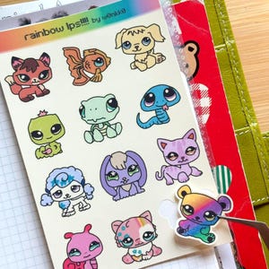 May include: A sheet of colorful stickers featuring various cartoon animal designs, including a fox, fish, dog, snake, and cat. The stickers are in a variety of colors, including pink, blue, green, and purple. Text at the top reads "rainbow lps!!!!" by wonkk@.