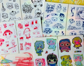 May include: A collection of sticker sheets featuring various hand-drawn illustrations in black, red, and full-color ink. The designs include cartoon characters, animals, and text such as A HONKY SKETCHBOOK, VOL. 2, and SKETCHBOOK VOL 003.