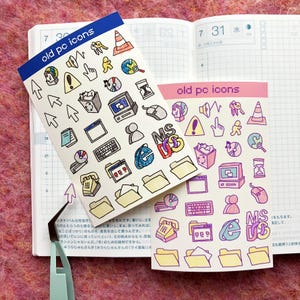 May include: Two sheets of stickers with old computer icons. The stickers are on a pink and white patterned surface. The stickers are white with black outlines and feature icons such as a floppy disk, a folder, a mouse, a speaker, a hard drive, and a computer monitor. The text on the stickers reads "old pc icons".