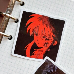 Puede incluir: Adhesivo cuadrado con una ilustraci&oacute;n de personaje de anime rojo sobre un fondo negro. El personaje tiene cabello rojo y una expresi&oacute;n decidida. El adhesivo est&aacute; sobre un fondo blanco, con un cuaderno y anillas visibles.