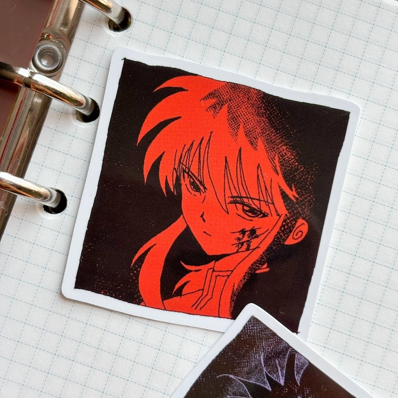 Puede incluir: Adhesivo cuadrado con una ilustraci&oacute;n de personaje de anime rojo sobre un fondo negro. El personaje tiene cabello rojo y una expresi&oacute;n decidida. El adhesivo est&aacute; sobre un fondo blanco, con un cuaderno y anillas visibles.