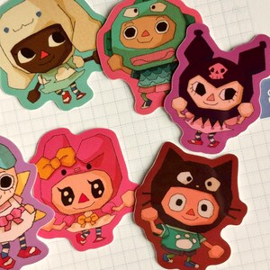 May include: A collection of colorful, die-cut stickers featuring cartoon characters. The stickers showcase various characters in different outfits and poses, with a variety of colors including pink, green, and brown. The stickers are arranged on a white surface.