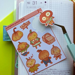 May include: A sheet of stickers featuring various pumpkin characters with different expressions and outfits. The stickers are on a light blue background with a pink border. The text "PUMPKINS" is written in a white font on a brown sign.
