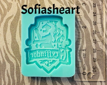 May include: A blue silicone mold of a Gryffindor crest with a lion, a shield, and the text "Gryffindor" in a banner.