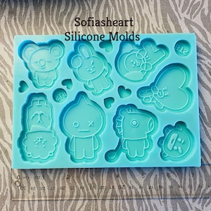 May include: A light blue silicone mold featuring various cartoon character designs, including a bear, bunny, and heart shapes. The mold has the text "Sofiasheart Silicone Molds" and a ruler for measurement.