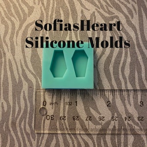 May include: A turquoise silicone mold with two coffin-shaped cavities. The mold is approximately 1 inch wide and is shown next to a ruler.