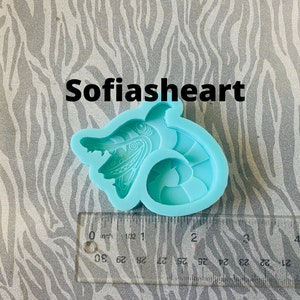 May include: A light blue silicone mold of a cartoon seahorse with a whimsical design. The mold is approximately 2 inches long and is sitting on a zebra patterned surface.