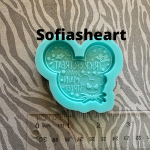 May include: A turquoise blue silicone mold shaped like Mickey Mouse's head. The mold features a design that says "Trick or Treat Down Main Street" with a jack-o'-lantern Mickey Mouse face.