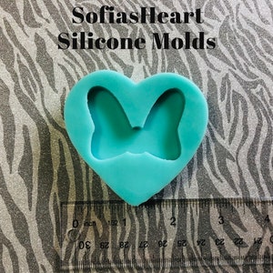 Puede incluir: Un molde de silicona azul claro en forma de coraz&oacute;n con un dise&ntilde;o de mariposa en el interior. El molde mide aproximadamente 5 cm de ancho.
