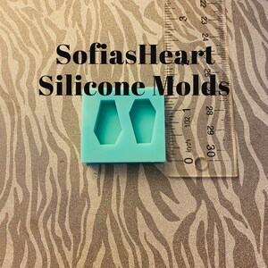 May include: A blue silicone mold with two coffin-shaped cavities. The mold is on a zebra-print surface with a ruler in the background. The text "SofiasHeart Silicone Molds" is visible in the image.