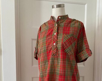 Puede incluir: Camisa de cuadros rojos, verdes y amarillos con cuello mandarín y mangas cortas. La camisa tiene un cierre de botón único en el cuello y un pequeño bolsillo en el pecho izquierdo.