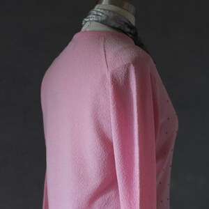 Peut inclure: Un pull rose avec un motif de pois subtils. Le pull est fait d'un mat&eacute;riau doux et duveteux et a des manches longues.