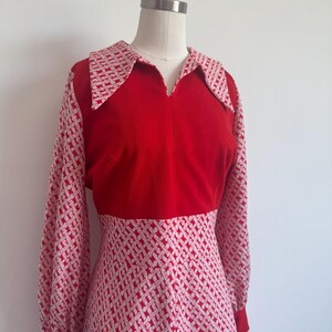 Könnte beinhalten: Ein rotes Vintage-Kleid mit weißem geometrischen Muster. Das Kleid hat lange Ärmel, einen Kragen und eine taillierte Taille. Die Ärmel und der Kragen haben ein weißes und rotes geometrisches Muster.