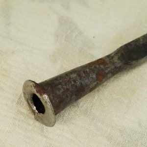 May include: A rusty metal tool with a flared end and a hole in the centre. The tool is likely used for a specific purpose, such as a woodworking tool or a blacksmithing tool.