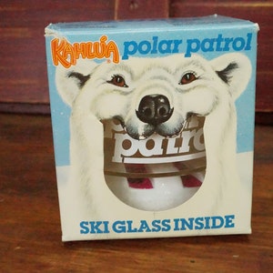 May include: A white box with a cartoon polar bear on the front. The box says "Kahlua polar patrol" and "Ski glass inside".