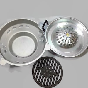 以下が含まれることがあります： 丸いグリルパン、丸いベース、黒い鋳鉄製のグリルグリルを備えたシルバーアルミニウム製のグリルセットです。