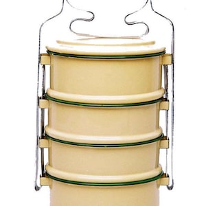 Op de afbeelding: Een vierlaags, crèmekleurige lunchbox met een groene rand en een metalen handvat.