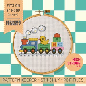 May include: A cross-stitch pattern in a 6-inch wooden hoop featuring a colorful toy train with a yellow duck and alphabet blocks on a white fabric background. Text reads FITS ON 6 INCH HOOP, 14 AIDA, BEGINNER FRIENDLY, and HIGH STRUNG cards.