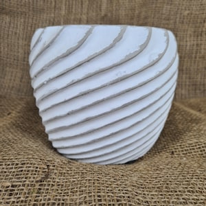 May include: White ceramic planter with a wavy, textured design. The planter is a light shade of white and has a rounded shape.