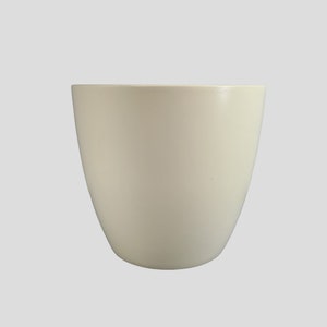 May include: A plain white ceramic planter with a rounded shape. The planter is empty and ready for a plant.
