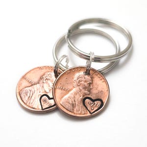 May include: Two copper-colored United States one-cent coins attached to silver-toned metal key rings. Each coin features a stamped heart outline containing the year 1978 and the letter D, positioned over the profile of Abraham Lincoln.