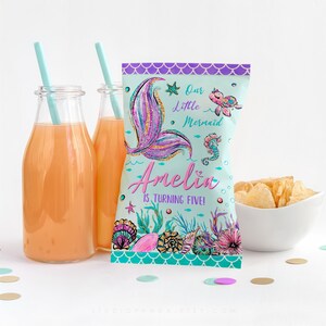 May include: A teal blue and purple mermaid-themed party favor bag with a glittery pink mermaid tail, a seahorse, and a turtle. The bag says "Our Little Mermaid Amelia is turning five!"