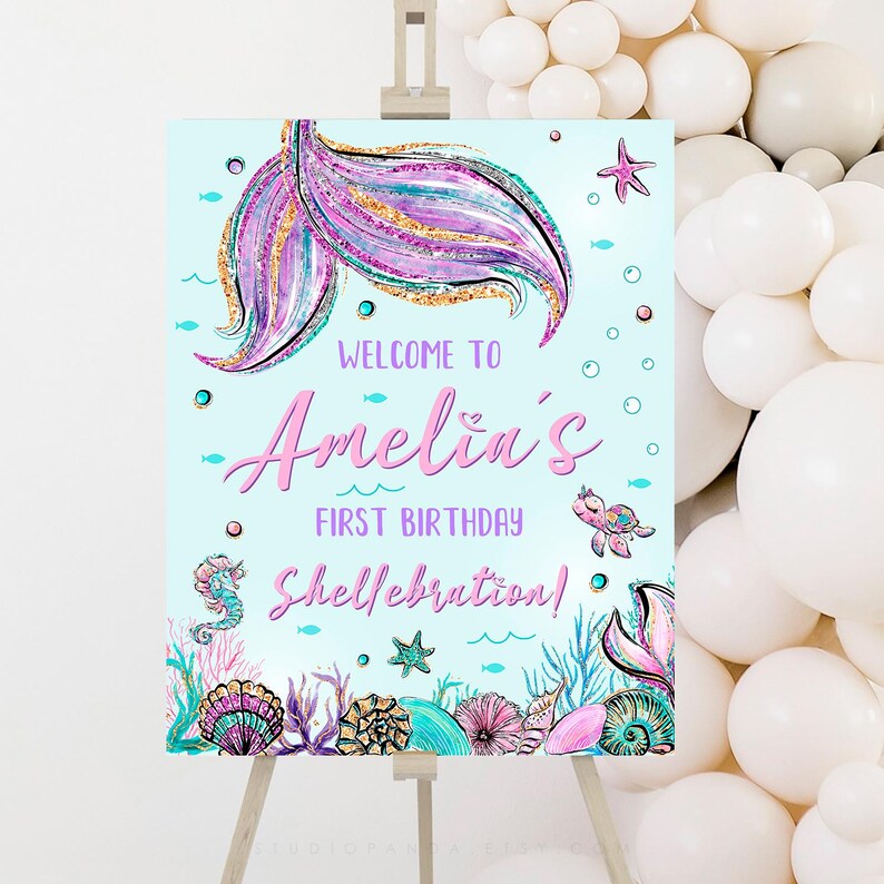 May include: A blue and purple mermaid tail with glitter accents on a light blue background. The text "Welcome to Amelia's First Birthday Shell-ebration!" is written in pink and white.