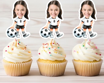 以下が含まれることがあります： カラフルなスプリンクルで飾られた3つのカップケーキ。サッカー選手のカップケーキトッパーが飾られています。各トッパーには、白のジャージに黒の番号8、黒のショートパンツ、黒のソックスを着用したサッカー選手の漫画が描かれています。サッカー選手は白黒のサッカーボールを持っています。