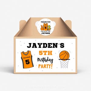 Puede incluir: Una caja de regalo blanca con temática de baloncesto. La caja tiene una etiqueta que dice "Jayden's 5th Birthday Party!" con un balón de baloncesto que pasa por un aro y una camiseta de baloncesto con el número 5. Hay una pegatina de agradecimiento en la parte superior de la caja que dice "Gracias Espero que te lo hayas pasado bien Jayden" con una camiseta de baloncesto y un balón de baloncesto.