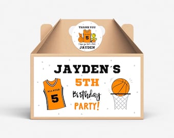 以下が含まれることがあります： バスケットボールをテーマにした白いギフトボックス。ボックスには「Jayden's 5th Birthday Party!」と書かれたラベルがあり、バスケットボールがフープを通過し、バスケットボールジャージに5番が書かれています。ボックスの上部には「Thank you I hope you had a ball Jayden」と書かれたサンキューシールがあり、バスケットボールジャージとバスケットボールが描かれています。