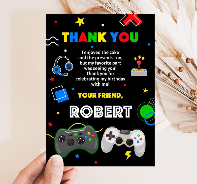 K&ouml;nnte beinhalten: Eine schwarze Dankeskarte mit buntem Text und Grafiken. Die Karte zeigt einen Videospiel-Controller, Kopfh&ouml;rer und den Text "THANK YOU" und "YOUR FRIEND, ROBERT".